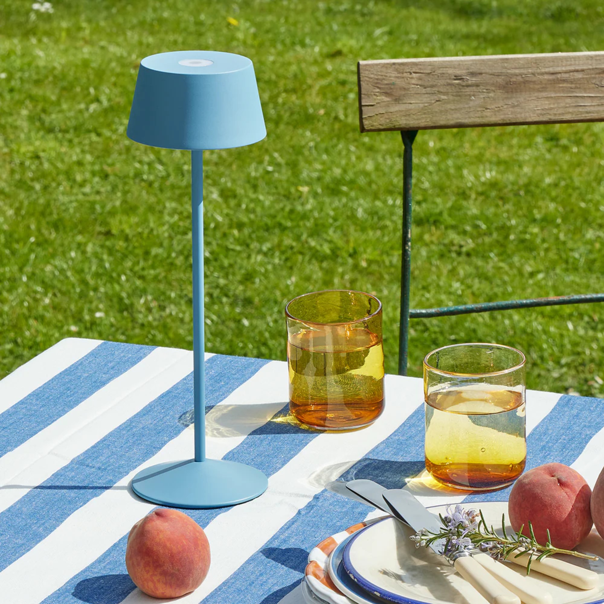 Pooky scoon rechargeable table lamp in Topaz on a garden dining table with a striped tablecloth