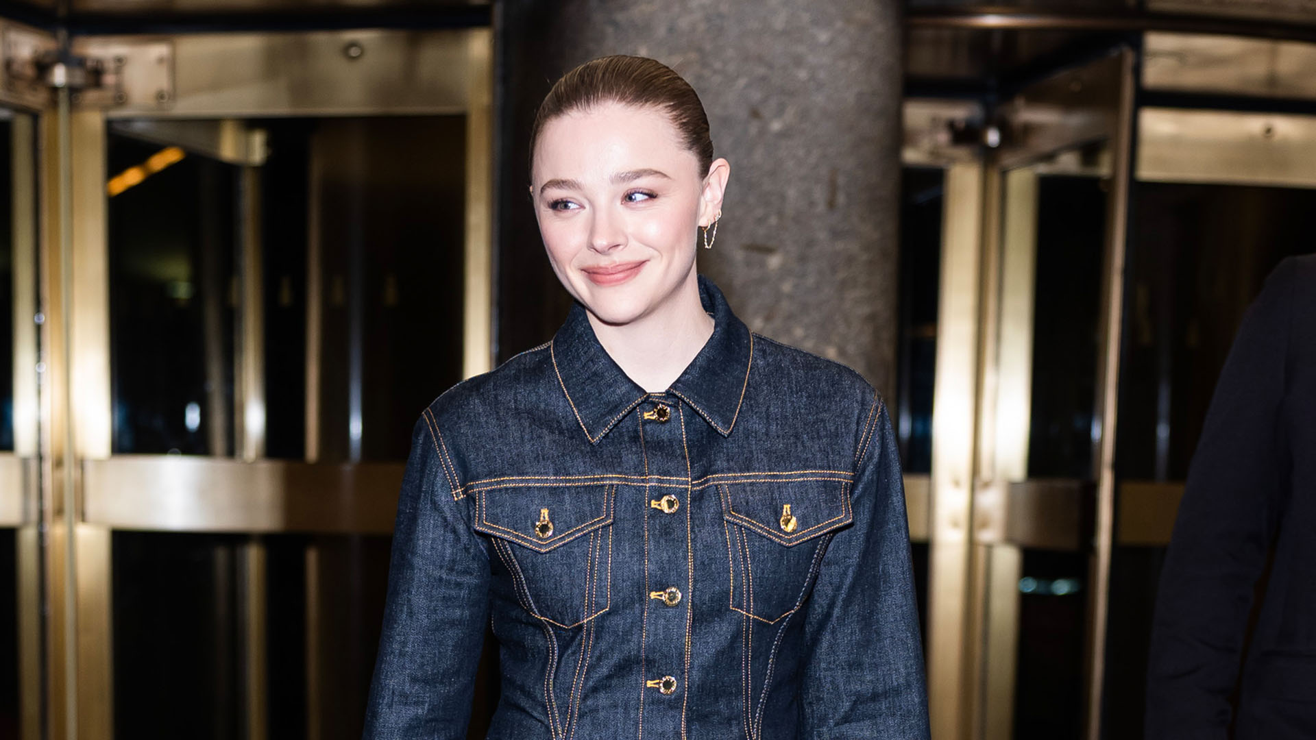 Chloe Grace Moretz wearing dark denim and Louis Vuitton Express bag.