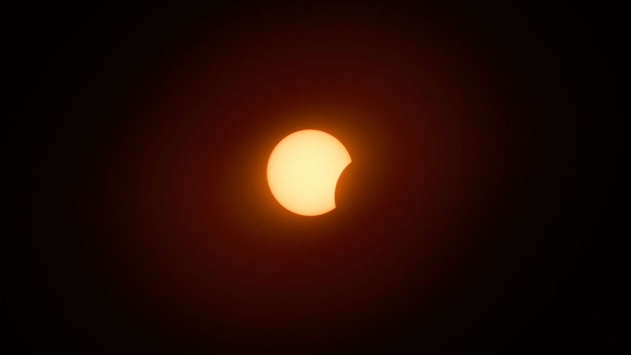 The eclipsed sun is photographed in a black sky during the partial phase of a total solar eclipse.