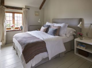 bedroom with windows and beams and wooden floor in brick-and-flint house