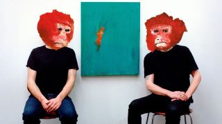 Steve Gullick and James Johnston sitting in a white room with red monkey masks on