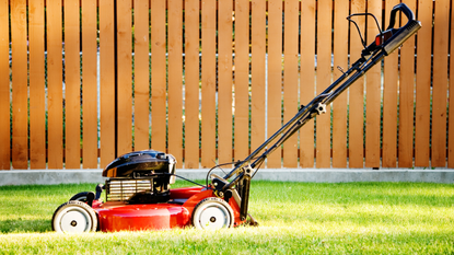 The best small lawn mowers 2023: Image depicts lawn mower in front of fence