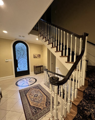 An entrance with yellow walls, a compass on the floor and stairway carpet