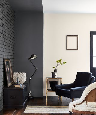 Contemporary living room painted cream and dark gray on walls and ceiling, dark wooden flooring, blue armchair, small striped rug, traditional armchair, black floor lamp