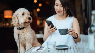 Woman drinking coffee sat at table with dog