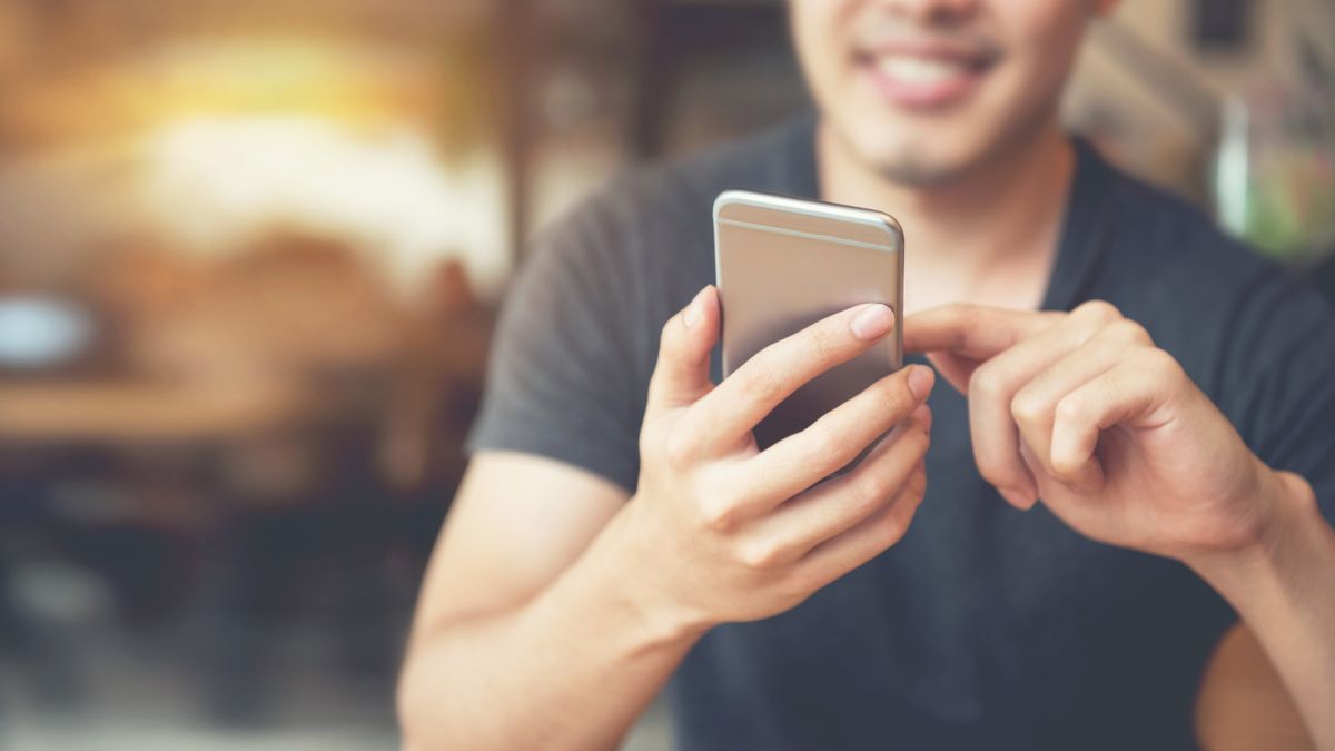 Smiling man using smartphone at a coffee shop