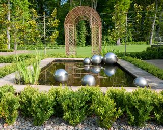 large rectangular pond with stone edge and modern sculpture features