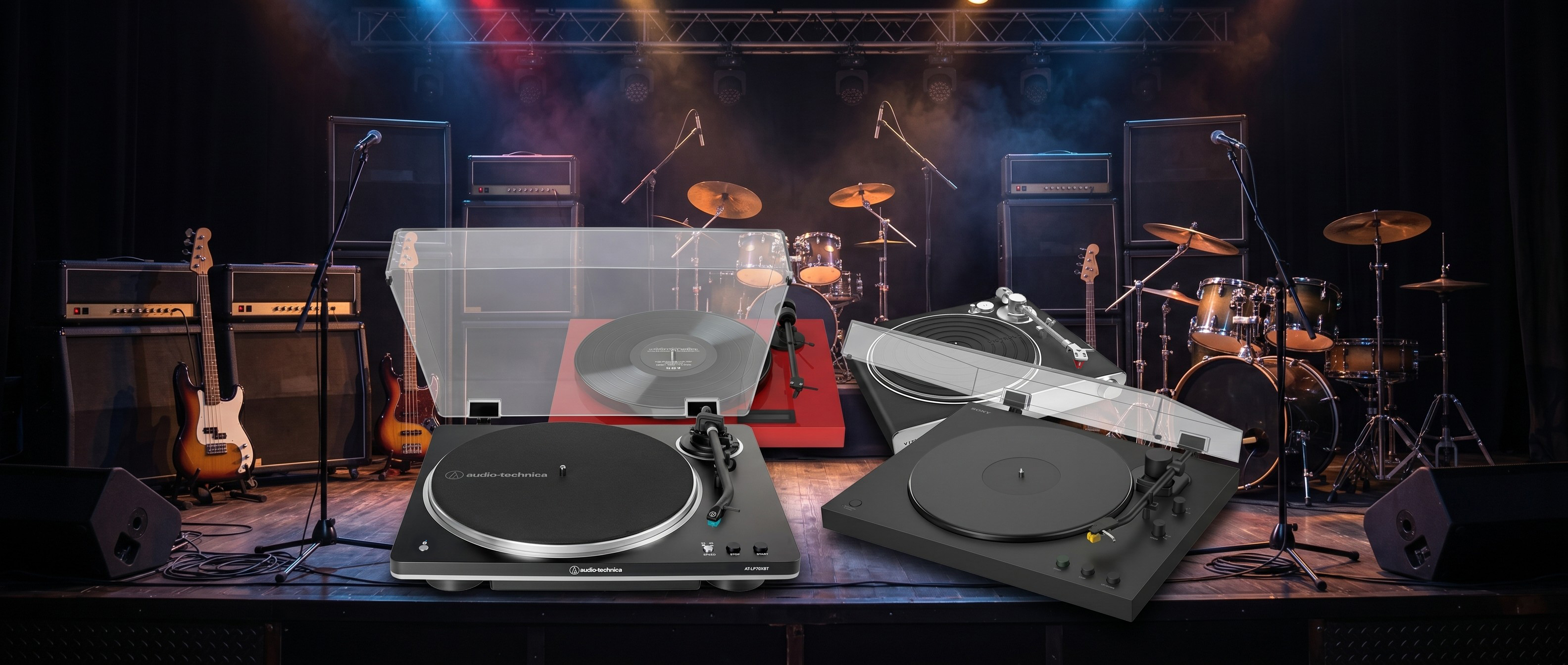 Audio-Technica AT-LP70XBT, Sony PS-LX5BT, Pro-Ject Juke Box E1 and Victrola Stream Carbon turntables on a concert stage surrounded by drums, guitars and speaker stacks