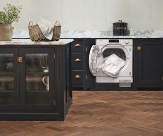 integrated heat pump tumble dryer in navy kitchen with wooden floor