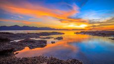 Yellow and orange-colored sunrise over the ocean and rocky coast