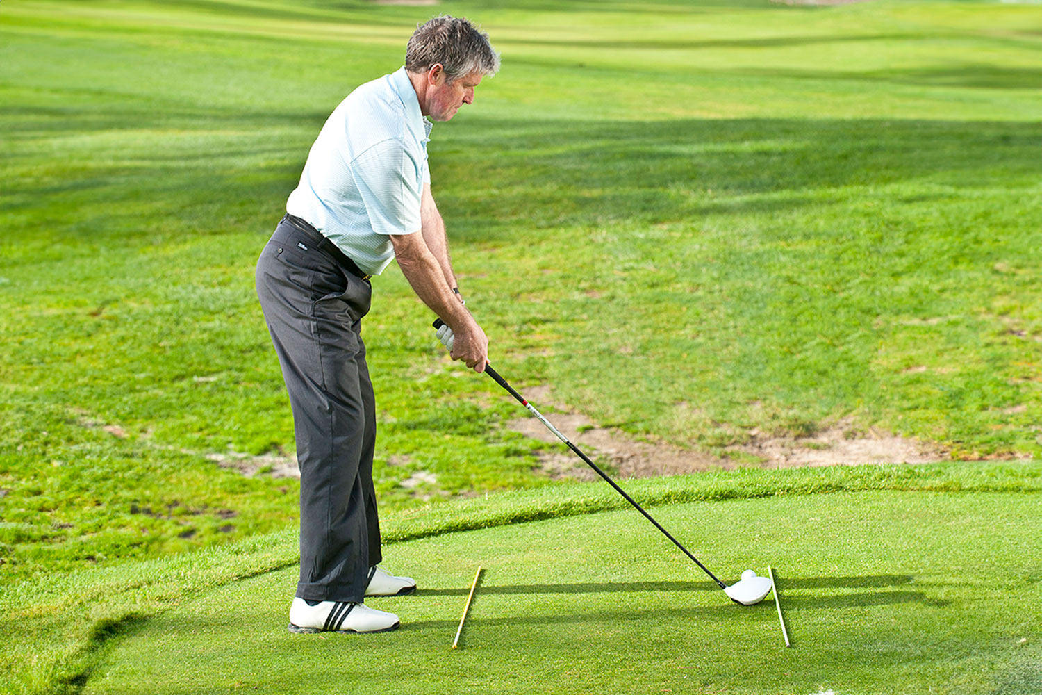 Andrew Reynolds demonstrating incorrect alignment, often leading to a slice, using two alignment sticks on the ground