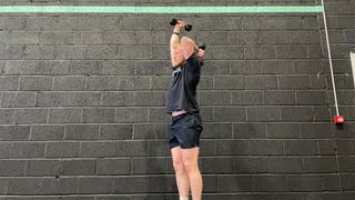 TechRadar fitness writer Harry Bullmore demonstrating an alternating dumbbell overhead triceps extension