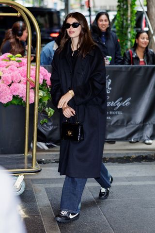 Kaia Gerber wearing head-to-toe black and Nike sneakers while at the Carlyle Hotel in New York City May 2024