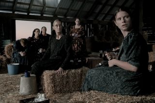 the cast of women talking sitting in a barn