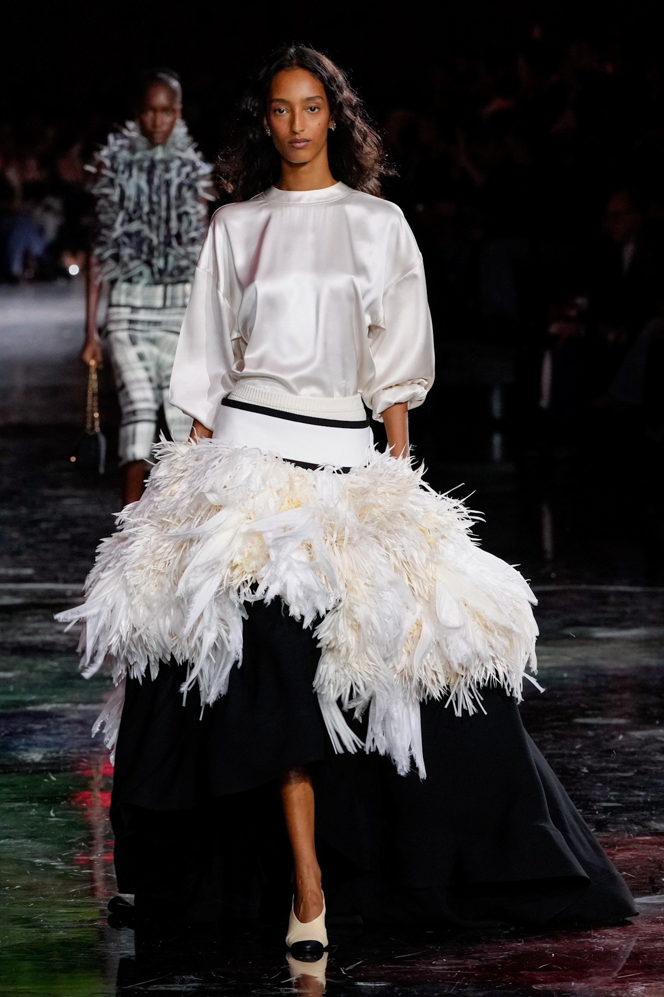 a model wearing a feathered skirt at the chanel show