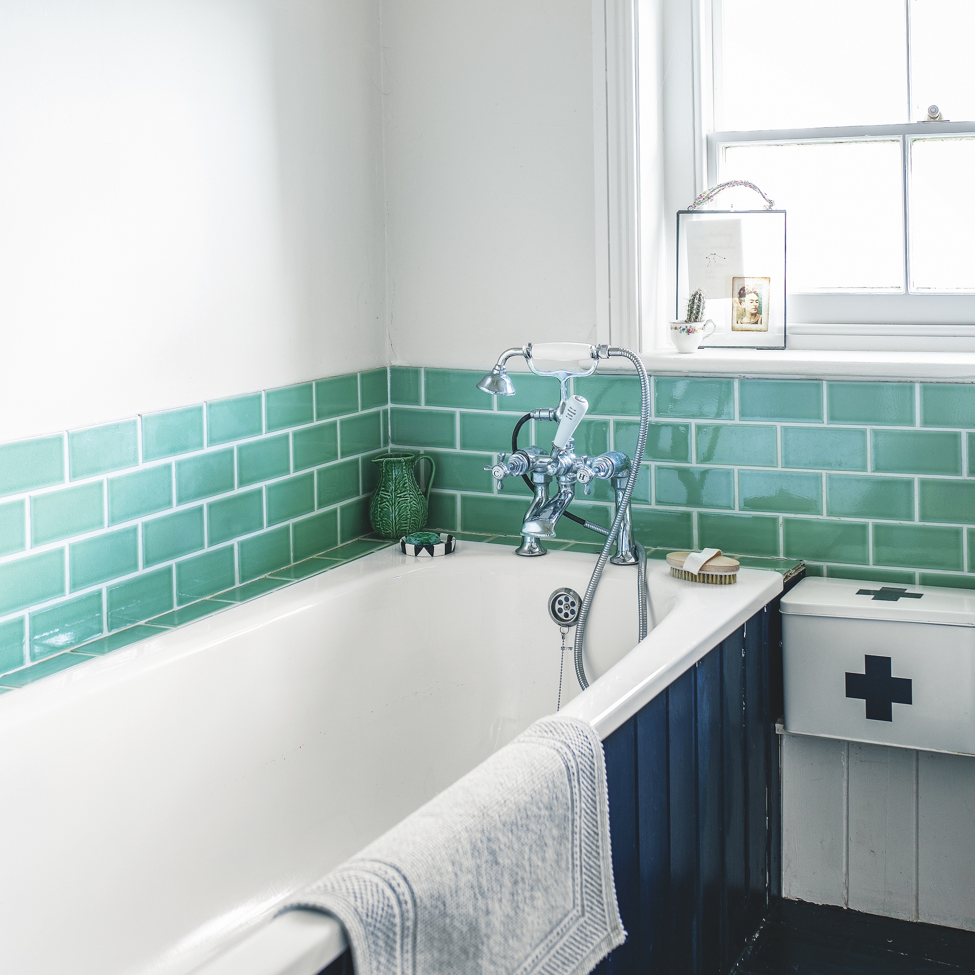bedroom with pink painted walls and double bed with patchwork quilt, with lamps on either side and photographs hung on wall above bed