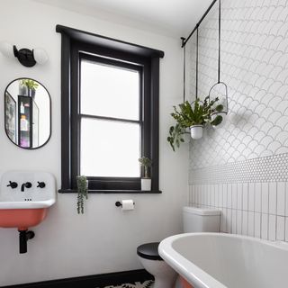 White bathroom with tiles walls, pink basin and hanging plants