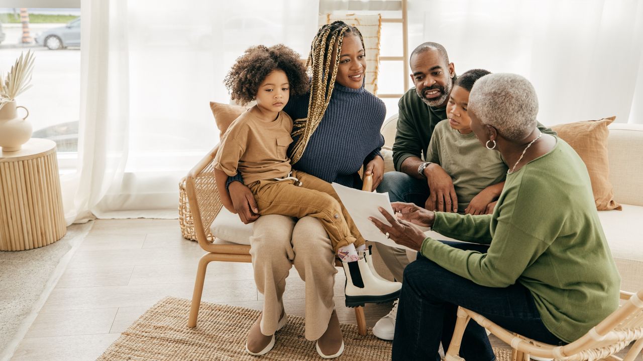 A young family gathers around an estate planner in their living room.