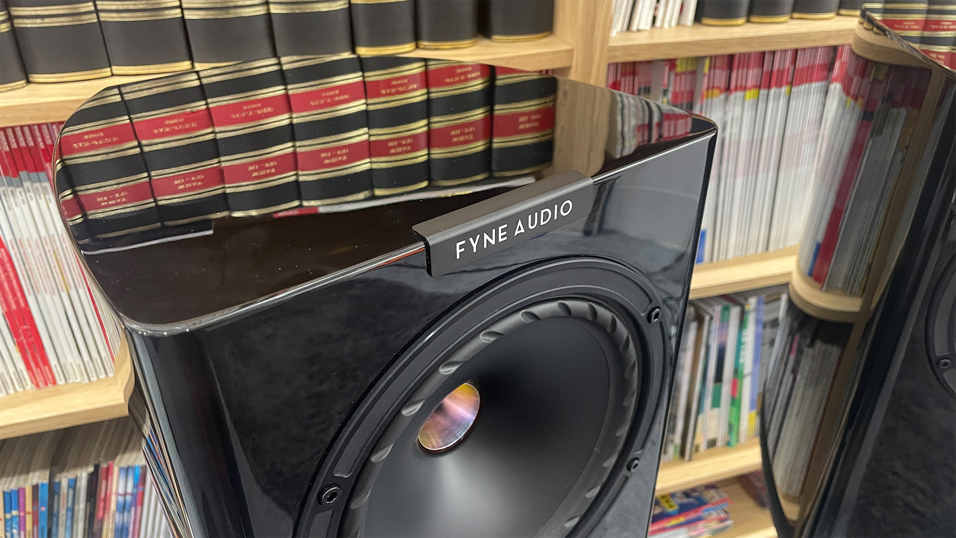 Fyne Audio F701SP standmount speakers top down showing Fyne Audio logo and reflective top in front of bookcase