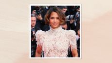 Image of Halle Berry smiling with curled brunette bob and wearing a cream lace dress, on a soft pink background
