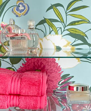 leaf wallpaper with towel on glass shelf with perfume bottles