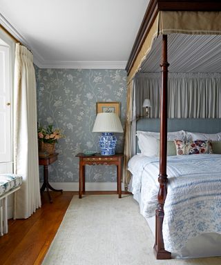 bedroom with blue patterned wallpaper and wooden four poster bed