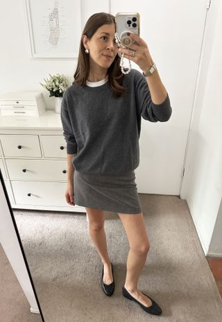 Woman in gray sweater and skirt.