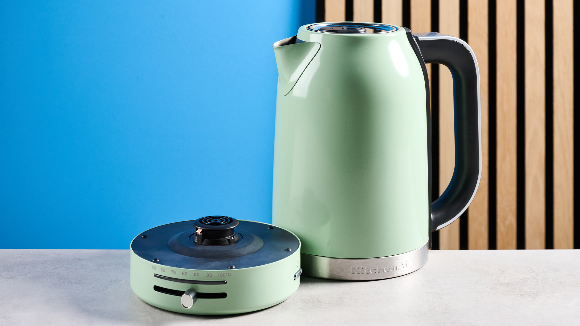 the kitchenaid 1.7L kettle in pistachio photographed on a white marble counter with a blue background