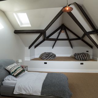 attic bedroom with white walls and bed with cushions
