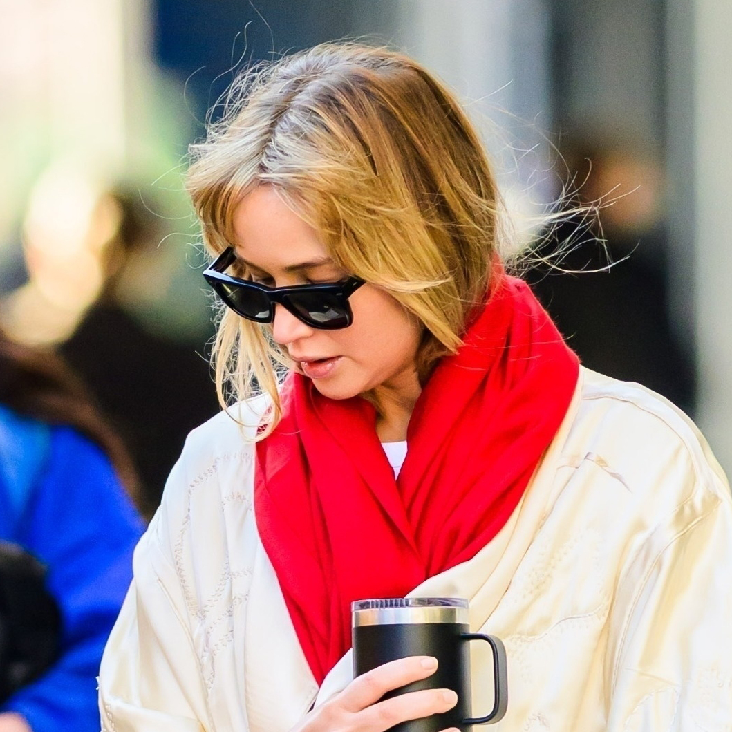 Jennifer Lawrence wearing a cream coat, red scarf, black pants, sneakers, and a Hermès Birkin bag in NYC