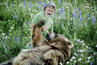 Naturalist Casey Anderson and his adopted bear Brutus in a meadow. Brutus is Anderson's "best friend."