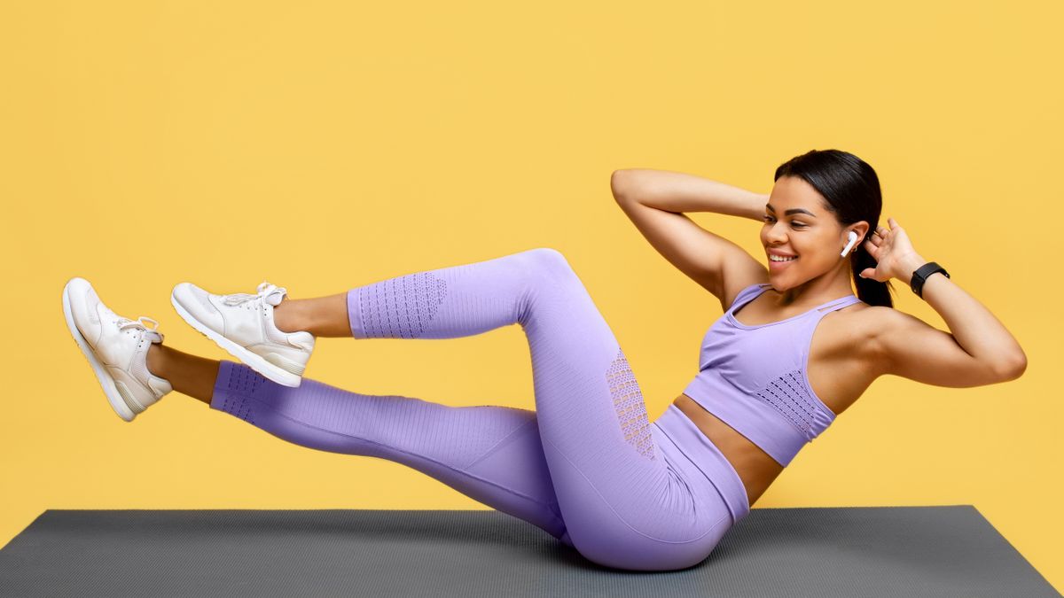 Woman performing bicycle crunches on a yoga mat in a yellow room