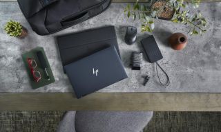An HP laptop on a slate-looking surface next to a few accessories