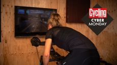 Woman riding indoor smart bike, with the Cycling Weekly Cyber Monday roundal