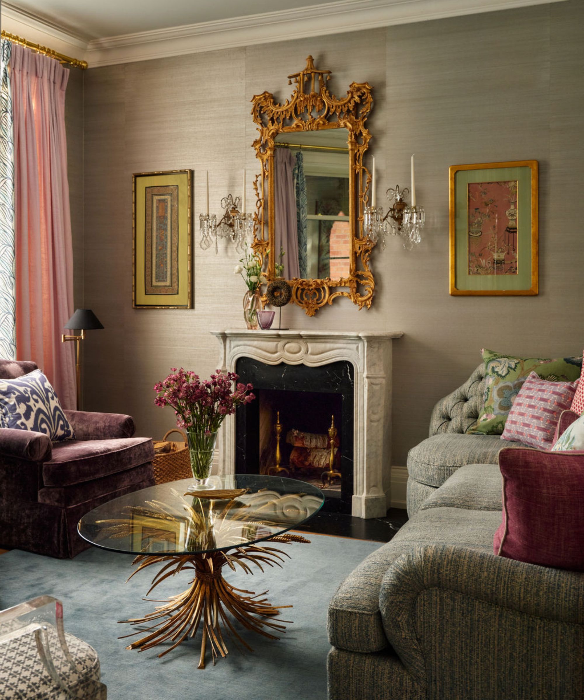 a grasscloth wallpapered living room with a Victorian marble fireplace, gold mirror and a touches of purples