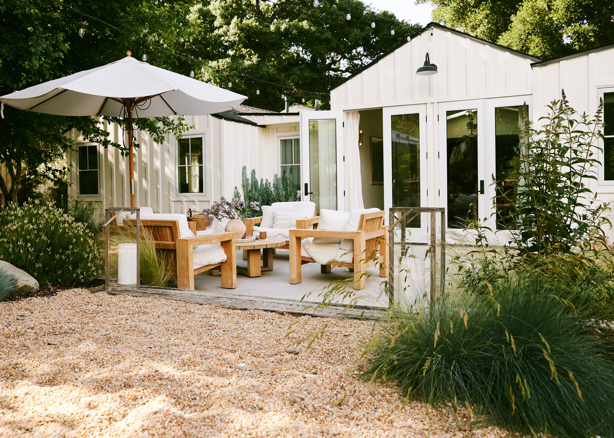 deck with garden furniture and umbrella, gravel landscaping and ornamental grasses