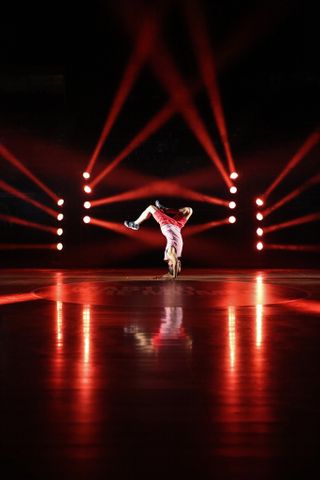 Canon EOS R5 Mark II sample image: a breakdancer dancing on a wooden floor, backlit with laser lighting