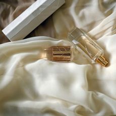 A gold perfume body mist on a cream silk dress