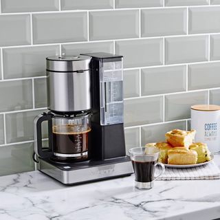 kitchen with grey tiles on wall and Coffee maker coffee cup on white designed counter
