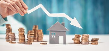 Woman holds an arrow down over model of the house and stack of coins.