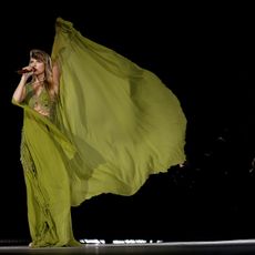 Taylor Swift in a flowy gown singing on tour
