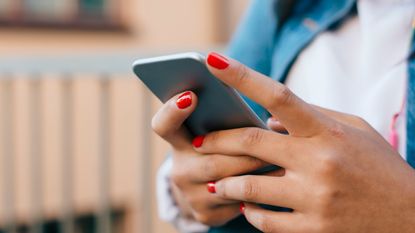 woman with red nail polish holding a phone 