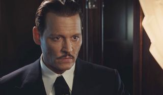 Johnny Depp In Murder On The Orient Express leans forward and looks intently at an unspecified objec