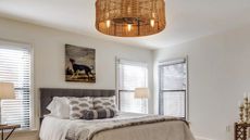 Gray bedroom with rattan light, dog print above the bed and gray headboard
