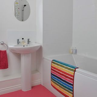 white bathroom with colourful floor and bathmat