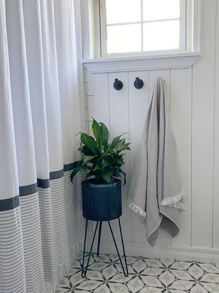 White guest bathroom with wall paneling and matching black rim mirrors