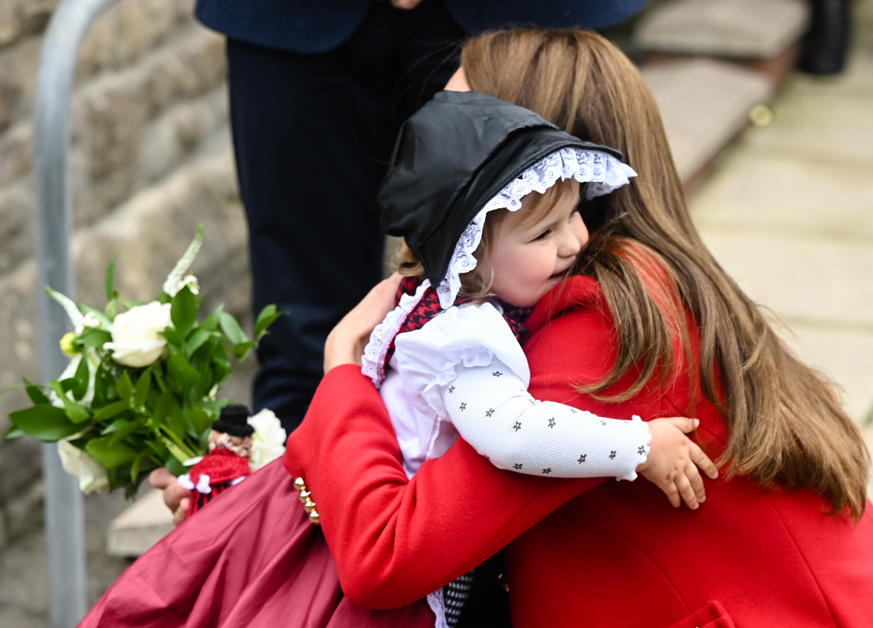Princess kate wearing a red coat hugging a little girl