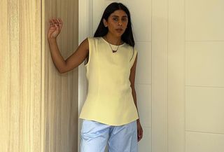 Influencer standing in butter yellow top and light blue pants.