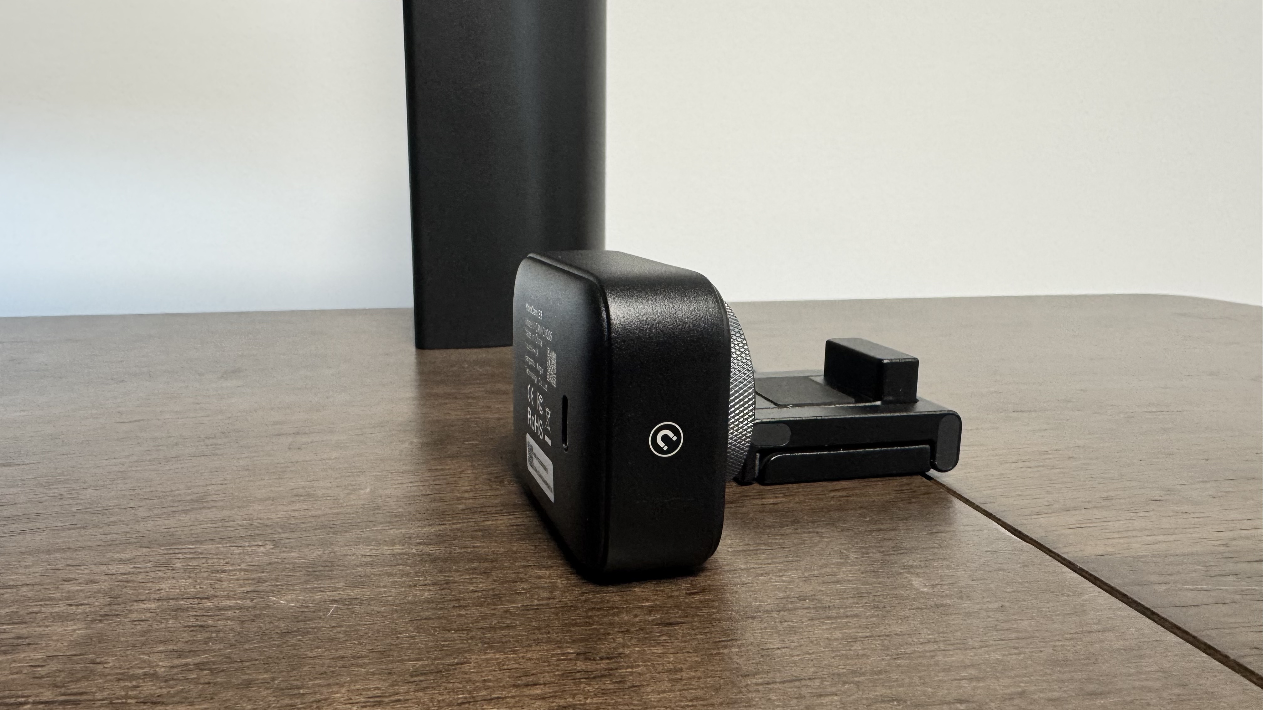 The Yololiv YoloCam S3 4K webcam from the right side, next to its stand on a wooden table