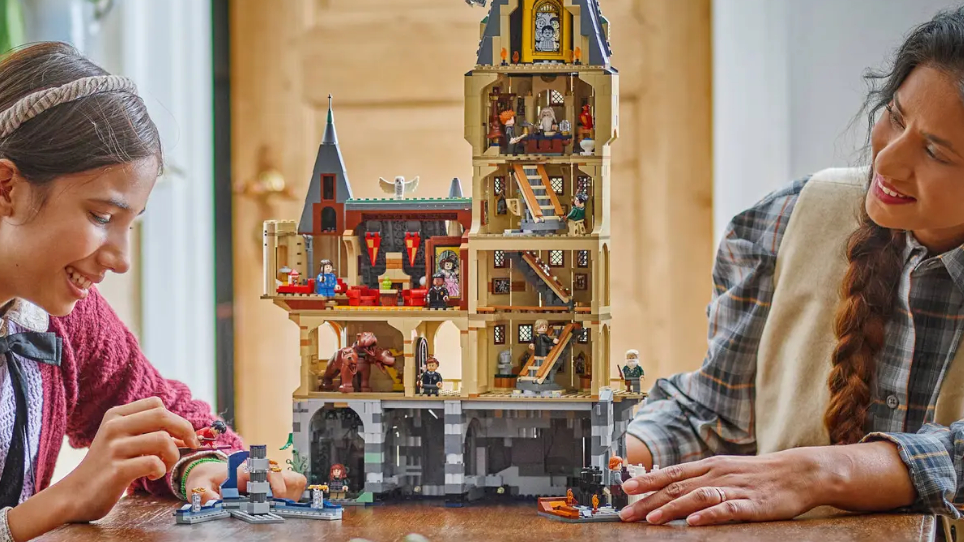 A woman and child smile as they build the Lego Hogwarts Castle: Main Tower